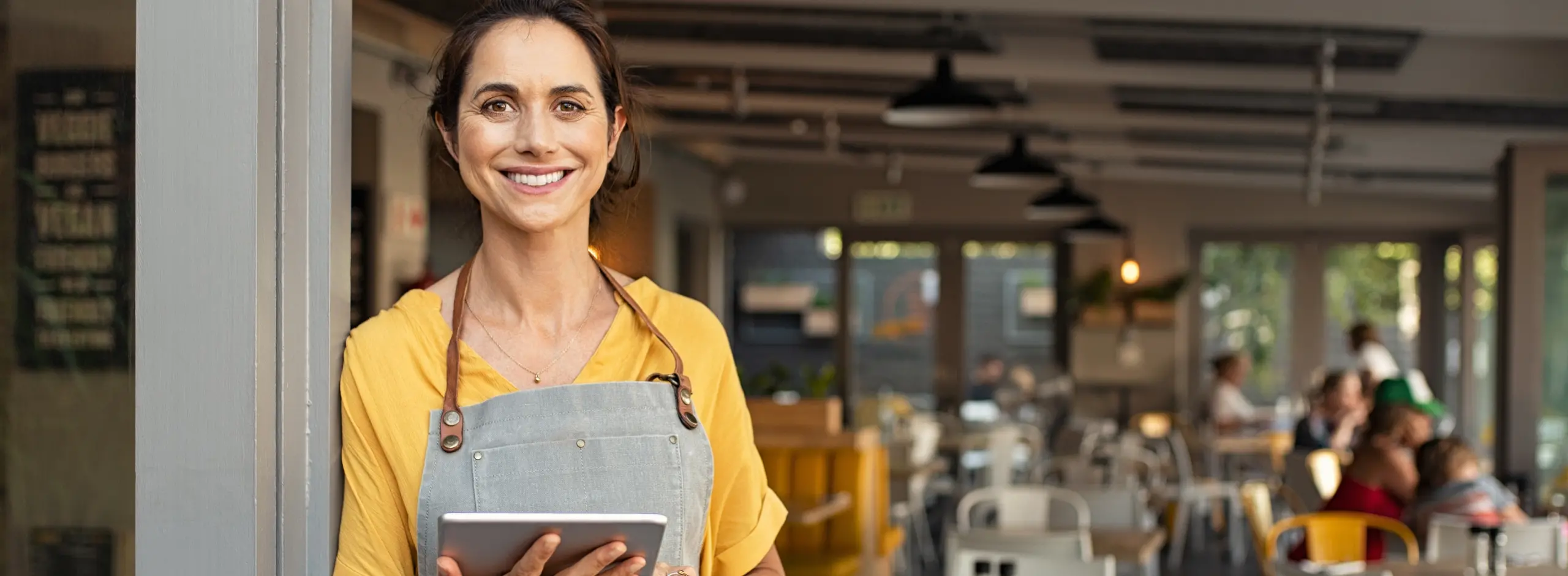Smiling Cafe Owner Holding Tablet