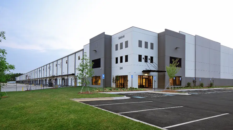 Modern gray industrial warehouse distribution building and parking lot